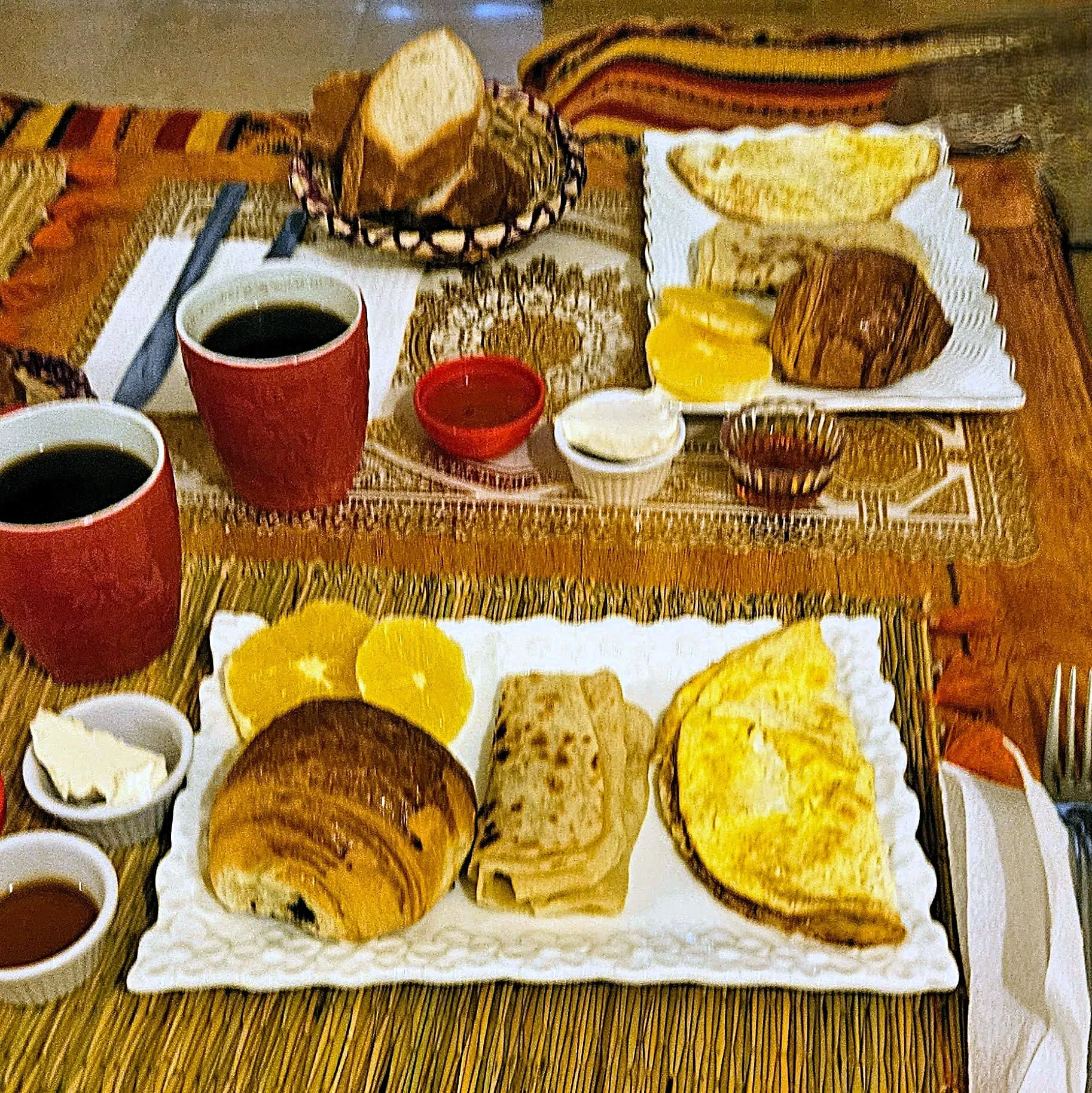 a plate with orange, a croissant, msemen and omelette
