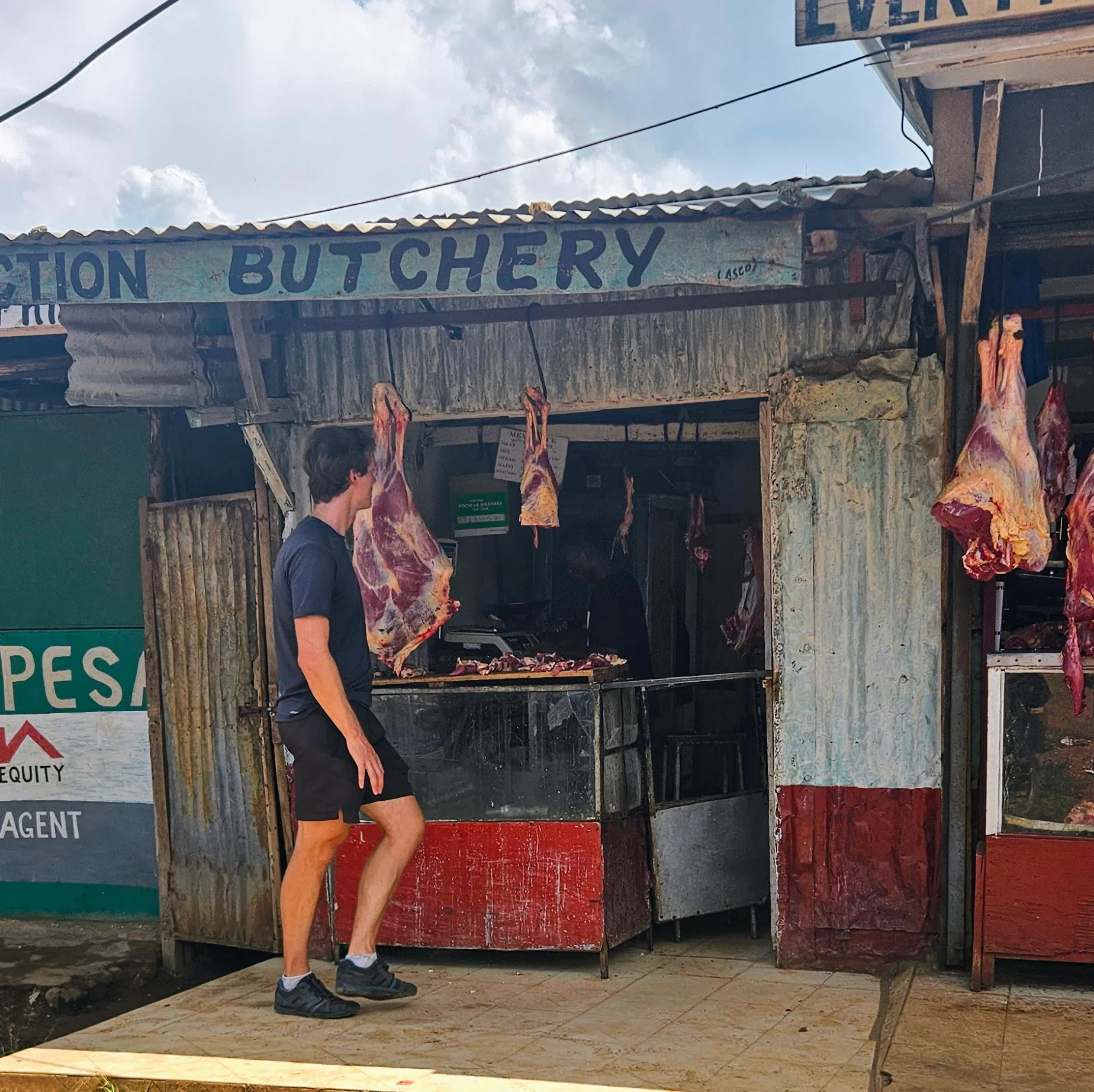 Will looking at a Kenyan butchery with whole carcasses hanging outside