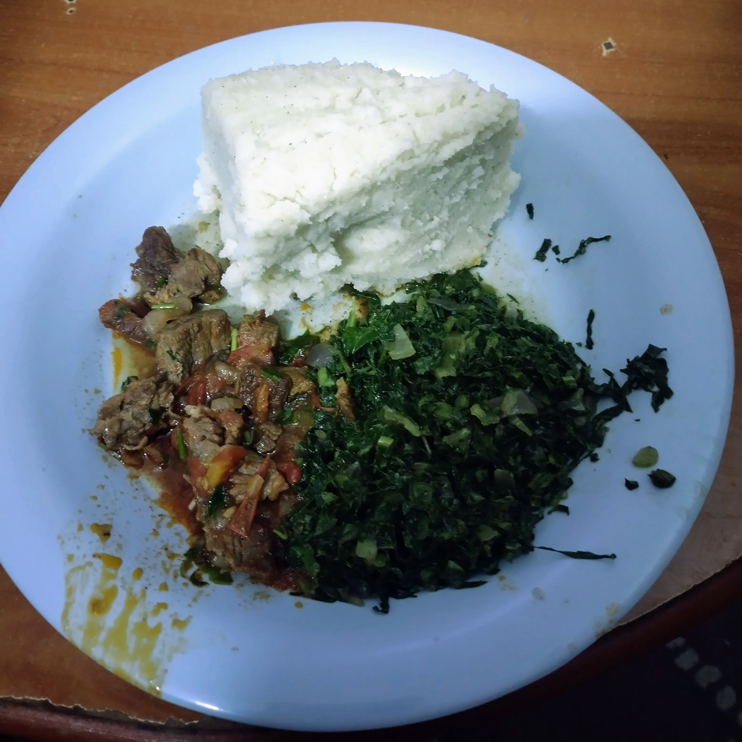 Plate of wet fry meat with ugali and sukuma wiki